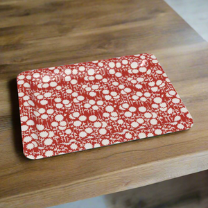 A rectangular tray featuring a vintage-inspired red and white floral pattern, placed on a warm wooden surface.