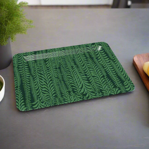 A nature-inspired decorative tray with a dark green fern motif, styled on a countertop near fresh herbs.