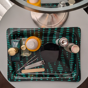 A patterned decorative tray used as a vanity organizer, holding perfume, skincare, and grooming essentials.