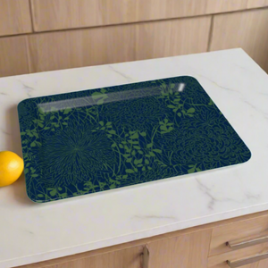 A rectangular tray with a dark blue and green floral design on a white marble kitchen counter, with light wood cabinets in the background.