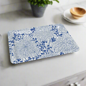A rectangular tray with a blue-and-white floral design on a white marble kitchen counter, with plates and a plant in the background.