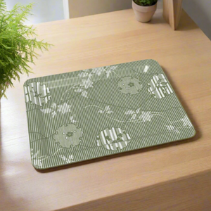Rectangular tray with a green and white yukiwa pattern showcasing floral-filled snow rings over subtle vertical stripes. Displayed on a natural wood tabletop with soft lighting and potted plants nearby.