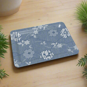 Rectangular tray with a blue and white yukiwa pattern featuring delicate floral motifs inside stylized snow rings, set against fine vertical stripes. The tray rests on a light wood surface surrounded by green foliage.
