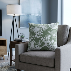 Gray armchair with a green floral pillow in a living room setting.