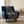 Woven blanket featuring a dark blue and off-white katagami pattern of stylized koi fish swimming through swirling waves and water currents, with a fringed edge, draped over a blue armchair.