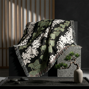 Decorative blanket with a leaf pattern draped over a stone surface in a minimalistic setting.