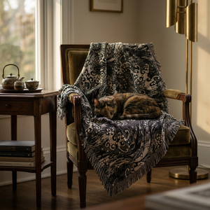 Cat sleeping on a patterned blanket draped over a wooden chair in a cozy room.