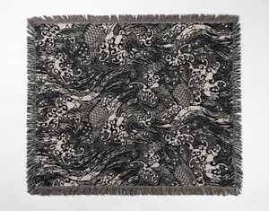 Dark blue and white woven blanket featuring a repeating pattern of carp (koi) swimming amidst dynamic waves and foam. 
