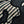 Close-up of a woven blanket featuring a traditional Japanese katagami design in black and off-white. The pattern includes stylized botanical motifs such as slender branches with small leaves or plum blossoms.
