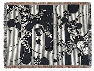 Woven blanket with a dark blue and white Japanese-inspired design. The pattern features a background of alternating vertical stripes and solid black shapes with undulating edges, overlaid with intricate white winding vines, leaves.