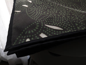 Microfiber and cotton terry towel with a black and green abstract circular ‘Fiesta’ pattern. Hemmed edges.