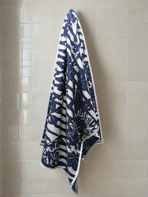 Microfiber and cotton terry towel hanging against a tiled wall, showcasing a dark blue and white ‘Trellis’ pattern. Hemmed edges add durability.