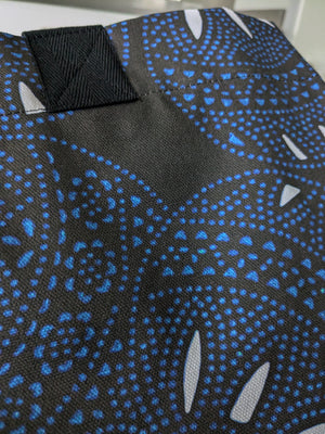 Black tote bag with a dynamic circular pattern in blue and white, featuring dotted and curved elements. Made from organic cotton canvas, ideal for stylish daily errands.