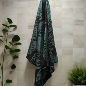 Microfiber and cotton terry towel in teal and black with a bold peony floral design. Soft, absorbent, and hemmed for durability.