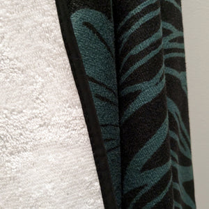 Microfiber and cotton terry towel in teal and black with a bold peony floral design. Soft, absorbent, and hemmed for durability.