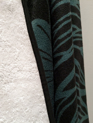 Microfiber and cotton terry towel in teal and black with a bold peony floral design. Soft, absorbent, and hemmed for durability.