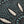 Woven blanket with a black background featuring scattered, irregular clusters of blue, green, and white threads.