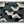 Woven blanket featuring a repeating Japanese katagami pattern of stylized pine (matsu) motifs. The design includes fan-like clusters of teal green pine needles and larger, abstract off-white shapes.