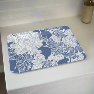A decorative tray with elegant white floral details on a blue background, placed on a clean, modern bathroom surface.