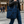 Black tote bag with a repeating blue stylized peony pattern, featuring fine, striated details within the blossoms, on a black background. The bag has black leather straps.