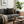 Cozy living room with a gray sofa, decorative pillows, a coffee table with books and a mug, and a plant.