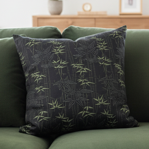 Green sofa with a decorative pillow and blanket in a living room setting.
