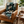 Brown leather armchair with a patterned green blanket, a wooden side table with a mug and book, and a potted plant in the background.