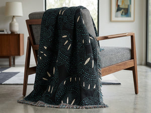 Decorative black blanket with white patterns draped over a chair in a living room setting.