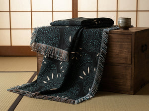 Dark patterned throw blanket draped over a wooden chest in a room with tatami flooring.