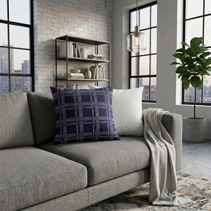Gray sofa with a blue patterned pillow and white blanket in a modern living room.